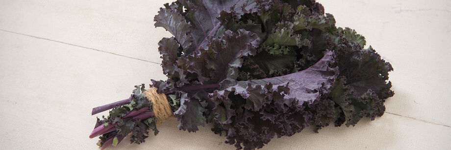 A bunch of red kale on a white board.